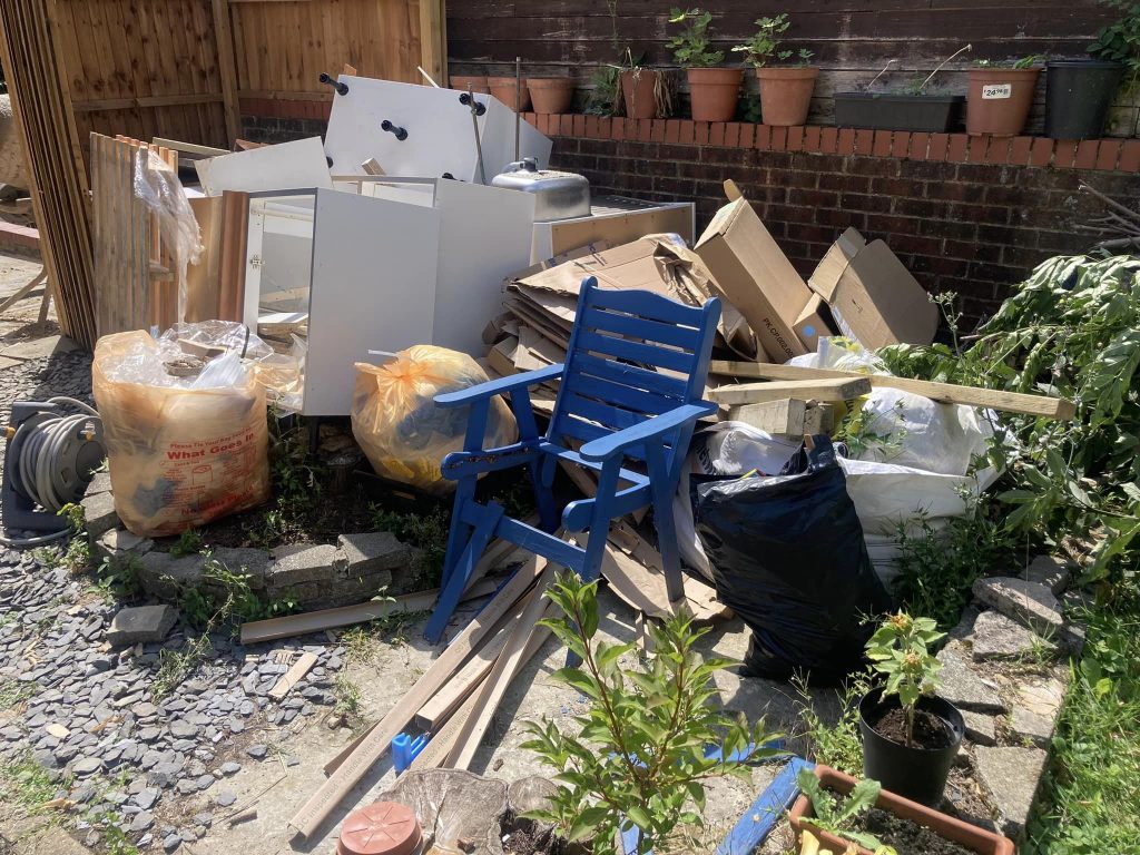 cluttered garden with lots of wooden waste with some old furniture wating for waste removal services from mangrove pwc