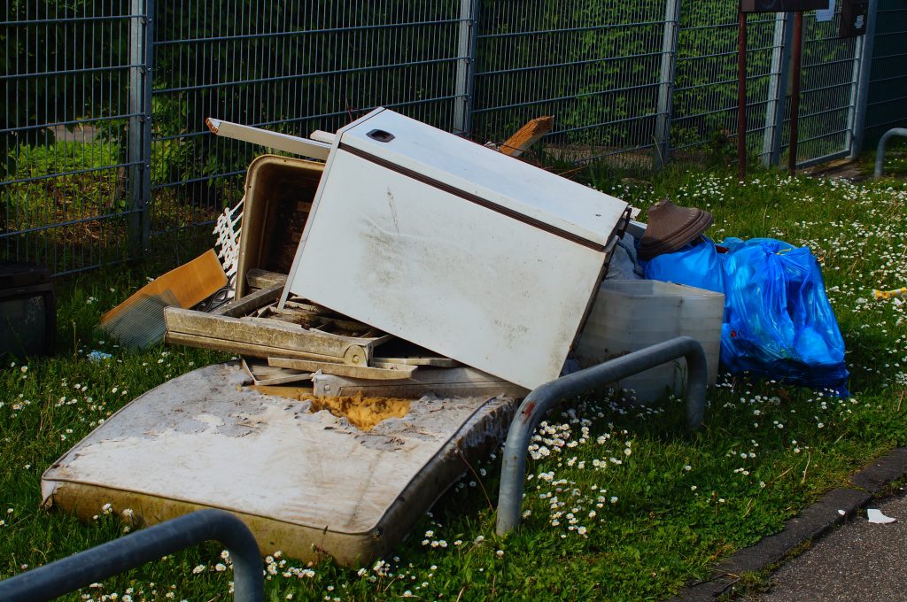 illegal fly tipping on the grass next to a path