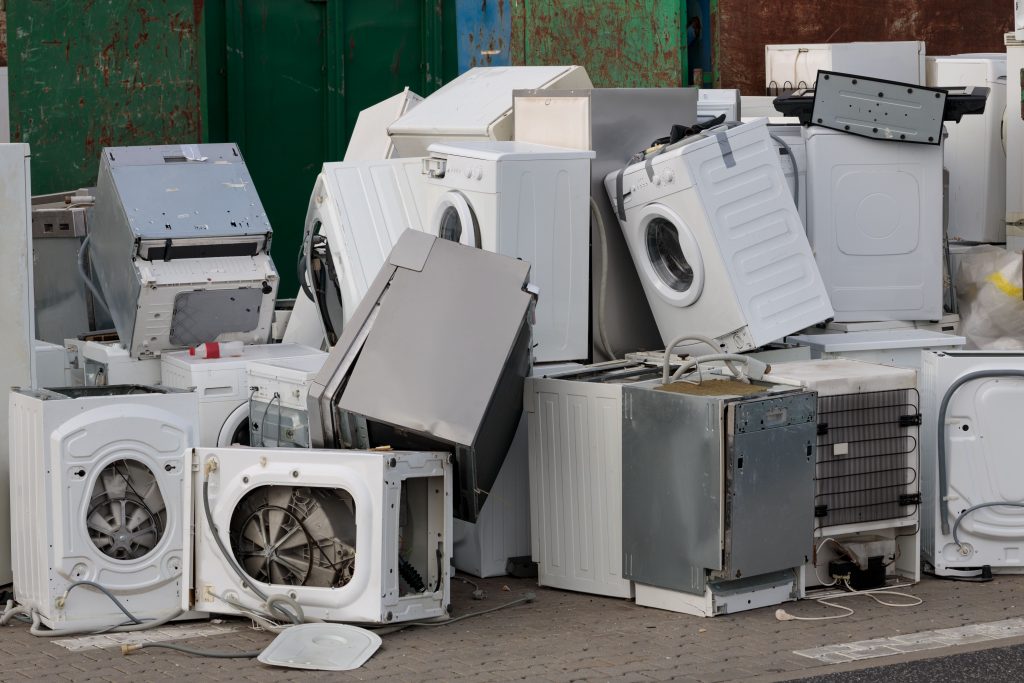 disregarded washing machines, dryers and other kitchen appliances in a pile representing white goods disposal